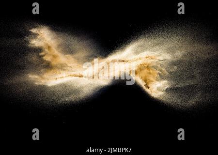 Golden sand explosion isolated on black background. Abstract sand cloud. Golden colored sand splash Stock Photo