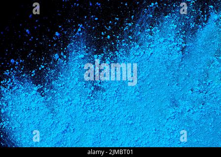 Blue color background of chalk powder. Blue color dust particles splattered on black background. Stock Photo