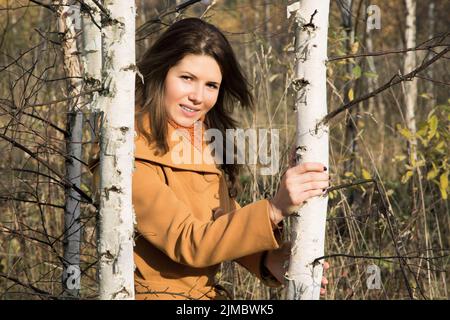 Girl in autumn day among young trees in the forest Stock Photo