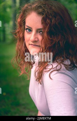 Attractive young woman with curly coppery hair Stock Photo