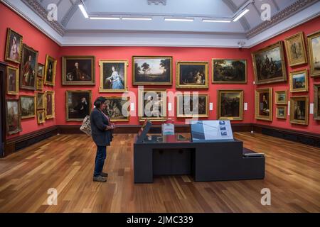 A woman looking at paintings in The McManus: Dundee's Art Gallery and Museum.