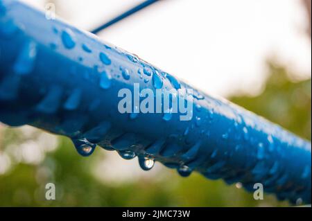 Raindrops on a blue metal pipe Stock Photo