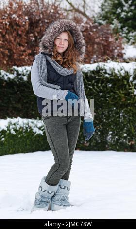 Girl in winter cloths standing in snow Stock Photo