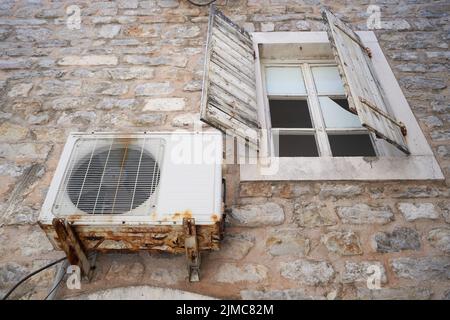 Old and rusty air conditioner compressor on the wall. Stock Photo