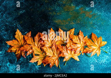 Bright red and yellow fake maple leaves on the concrete background Stock Photo