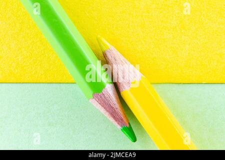 Color pencils on yellow and green color papers arranged diagonally. Stock Photo