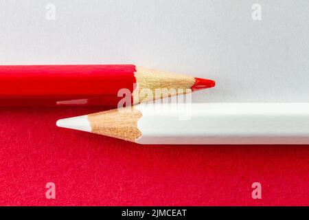 Color pencils on red and white color papers arranged horizontally. Stock Photo