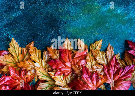 Bright red and yellow fake maple leaves on the concrete background Stock Photo