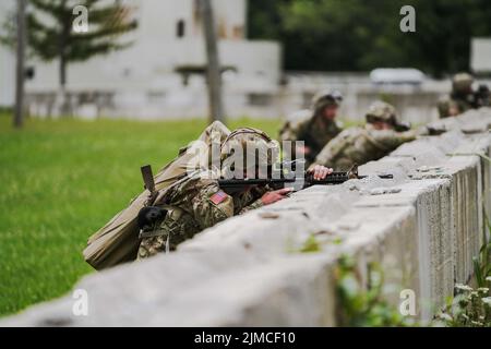 Infantrymen with Company B. 1st Battalion 151st Infantry Regiment alongside cavalry scouts and mortarmen conduct urban training at Muscatatuck Urban Training Center, Ind., Tuesday, Aug. 2, 2022. Guardsmen pull security over a barricade during an annual training exercise. Participating in realistic training scenarios is how the Indiana National Guard maintains a lethal fighting force. Stock Photo