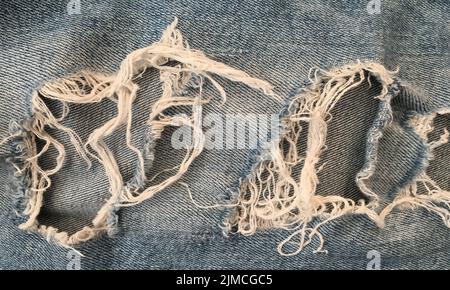 Ripped denim jeans background. Texture of denim or blue jeans background. Stock Photo