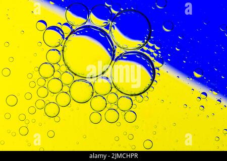 Abstract Background of Oil Bubbles on Water Surface yellow blue colorful palette. Stock Photo