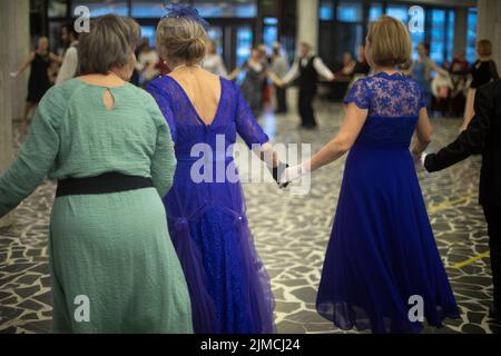 Dancing at meeting of old friends. Score in ball gowns.
