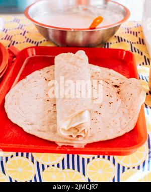 Food Traditional Large Quesillo served on table. Nicaraguan cheese made and served on the table. Traditional cheese with pickled onion and wrapped Stock Photo