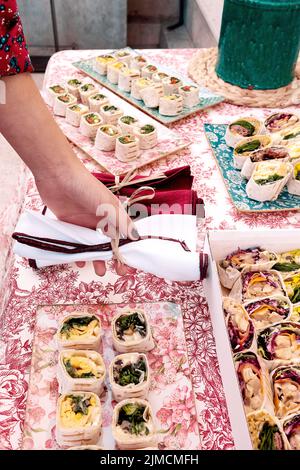 Crop anonymous person arranging napkins on table with set of fresh delicious tortilla rolls served for festive event celebration Stock Photo