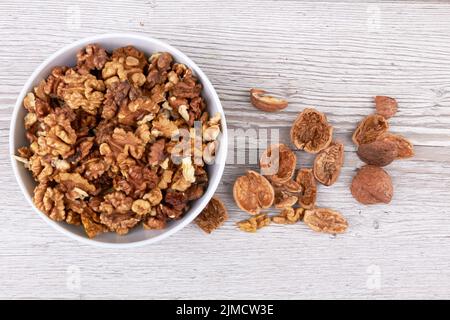 Walnuts in white bowl on wooden surface Stock Photo