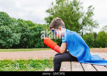 Little boy in superhero costume and with awareness ribbon on red ...