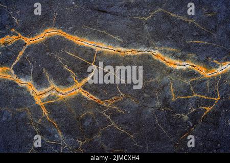 Closeup of rough uneven texture of rocky cliff with cracks as abstract background Stock Photo
