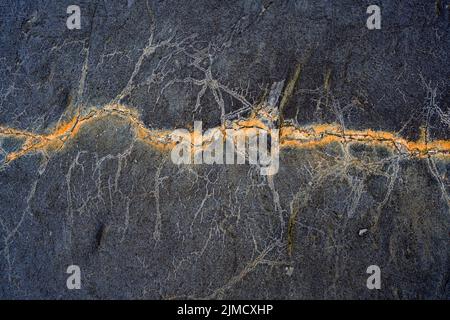 Closeup of rough uneven texture of rocky cliff with cracks as abstract background Stock Photo