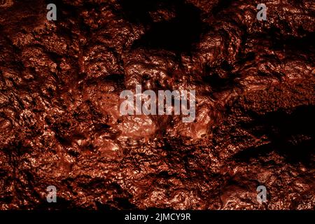 Rough brown textured wall of lava cave with uneven surface as abstract background Stock Photo