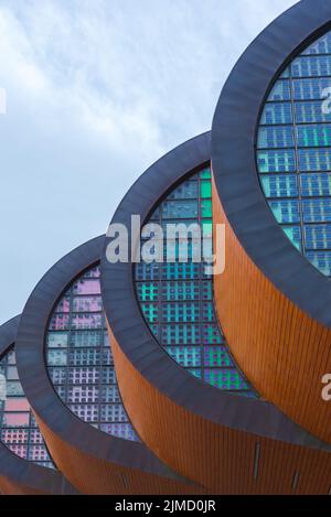 Facades of contemporary round shaped buildings with unusual architecture and modern style located against on street against blue sky in city Stock Photo