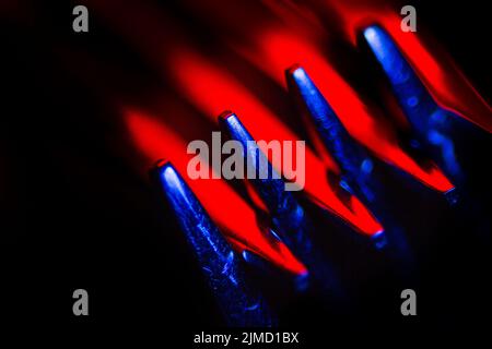 Two forks in colorful illumination macro shot creating an abstract composition suitable as a background. Stock Photo