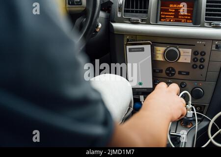 Cropped unrecognizable male with navigator on mobile phone driving modern car on road Stock Photo