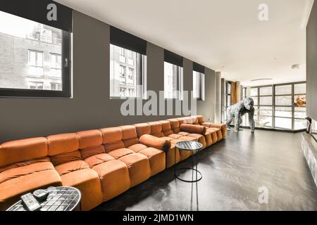 Comfortable orange sofa placed near fireplace in cozy spacious living room in modern house