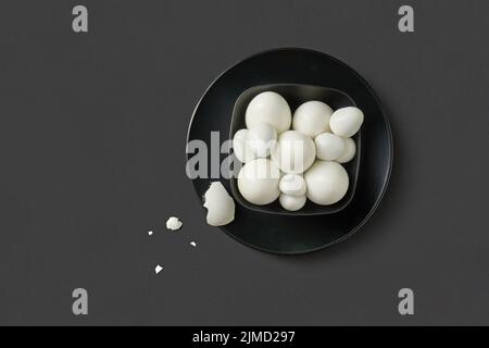 Fresh farm chicken and quail eggs boiled on a black plate on a dark background. Stock Photo
