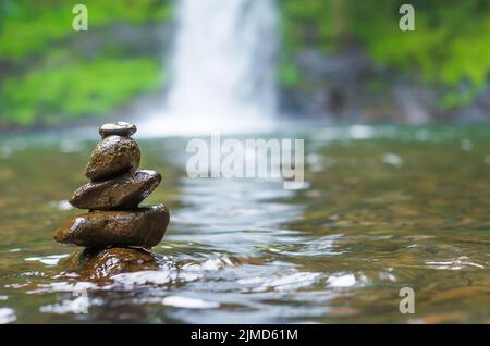 Great concept of spiruality, tranquility and meditation, land art with stones in waterfall. Stock Photo