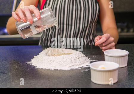 Woman preparing pizza dough on black granite table Stock Photo