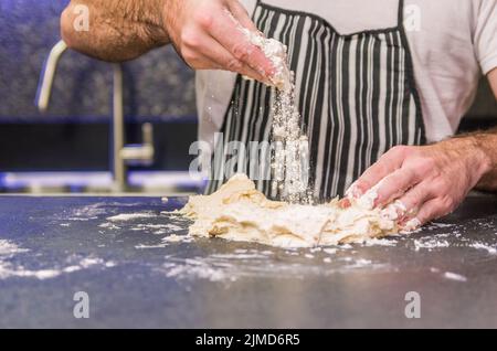 Man preparing pizza dough on black granite table Stock Photo