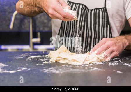 Man preparing pizza dough on black granite table Stock Photo