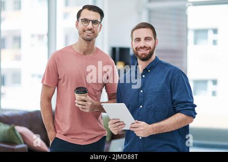 We bring nothing but authenticity to our brand. two young businessmen using a digital tablet together in a modern office. Stock Photo