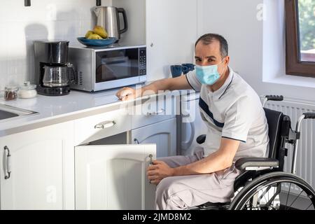 Young man wearing face mask sitting in front of kitchen Stock Photo