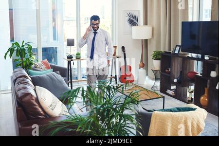 Dressing up looks a little different when working from home. a man talking on his cellphone while working from home. Stock Photo