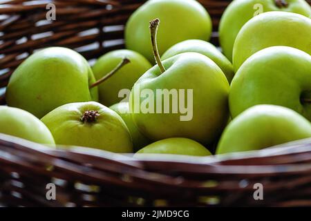 Green apples freshly picked in wicker basket, close up Stock Photo