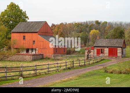 Red barn and log cabin on dirt road at historic Daniel Boone Homestead Stock Photo