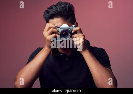 Look for the beauty in life. Studio shot of a young man holding up a camera. Stock Photo
