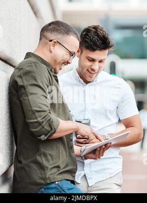 Great connectivity for those impromptu collaborations. two young businessmen using a digital tablet together against an urban background. Stock Photo