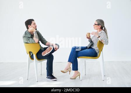 Success is always the main topic of discussion. two businesspeople having a discussion while sitting on chairs in an office. Stock Photo