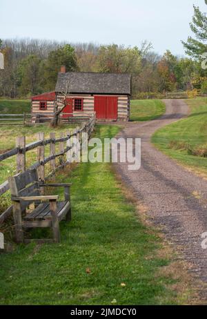 Empty bench along rustic rural lane by log cabin. Stock Photo