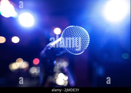 Round microphone in the rays of multi-colored lamps on the concert stage Stock Photo
