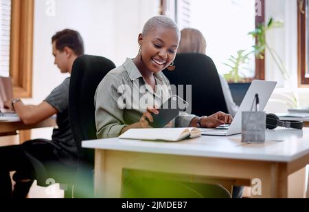 Checking her notifications. a young businesswoman using a cellphone while working in an office. Stock Photo