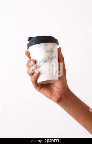 A coffee will make all the worries go away. Studio shot of an unrecognizable woman holding a reusable coffee cup against a white background. Stock Photo