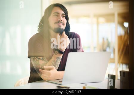 You level of dedication matters a lot. a young businessman looking thoughtful while working on a laptop in an office. Stock Photo