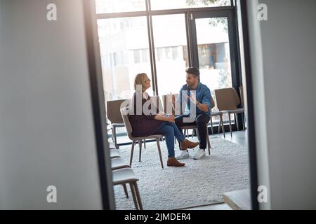 Young businessman talking to his therapist after a therapy meeting at a psychology office for mental health problems. Male employee having a Stock Photo
