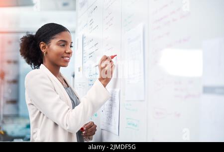 Project manager writing on a whiteboard to plan ideas and visualize business strategy. Focused, confident and thoughtful businesswoman showing Stock Photo