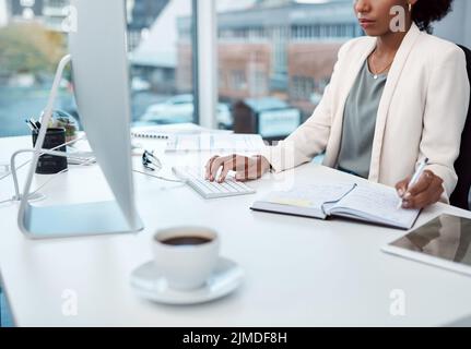 Writing notes, typing on a computer and working at her desk with a corporate and professional business woman. Manager, boss or CEO scheduling Stock Photo