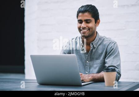 Know your worth then work to prove it. a young businessman using a laptop and having coffee in a modern workplace. Stock Photo