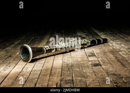 Black woodwind clarinet lies on a brown wooden stage Stock Photo